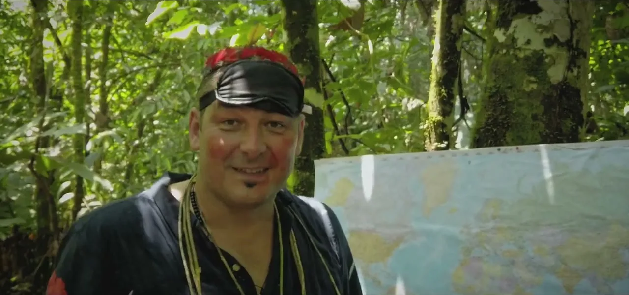 Sorin blindfolded and face-painted beside a world map after a blow-dart throw