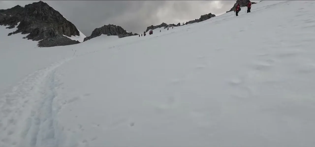 Expedition travellers hiking up a snowy slope after landing at Orne Harbour, Antarctica