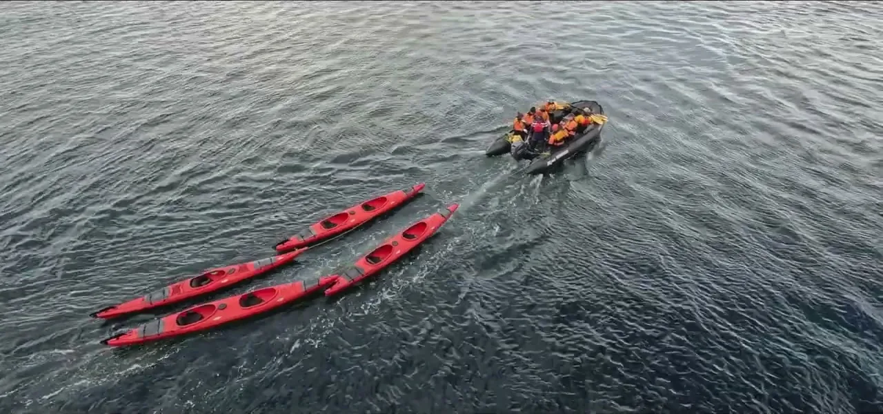 Aerial view of red sea kayaks and a Zodiac on the still water among Antarctic islands