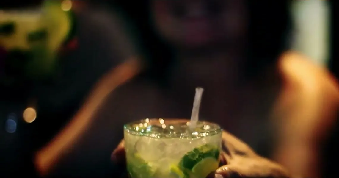 A hand holding a caipirinha cocktail with lime and sugar, Brazil's national drink