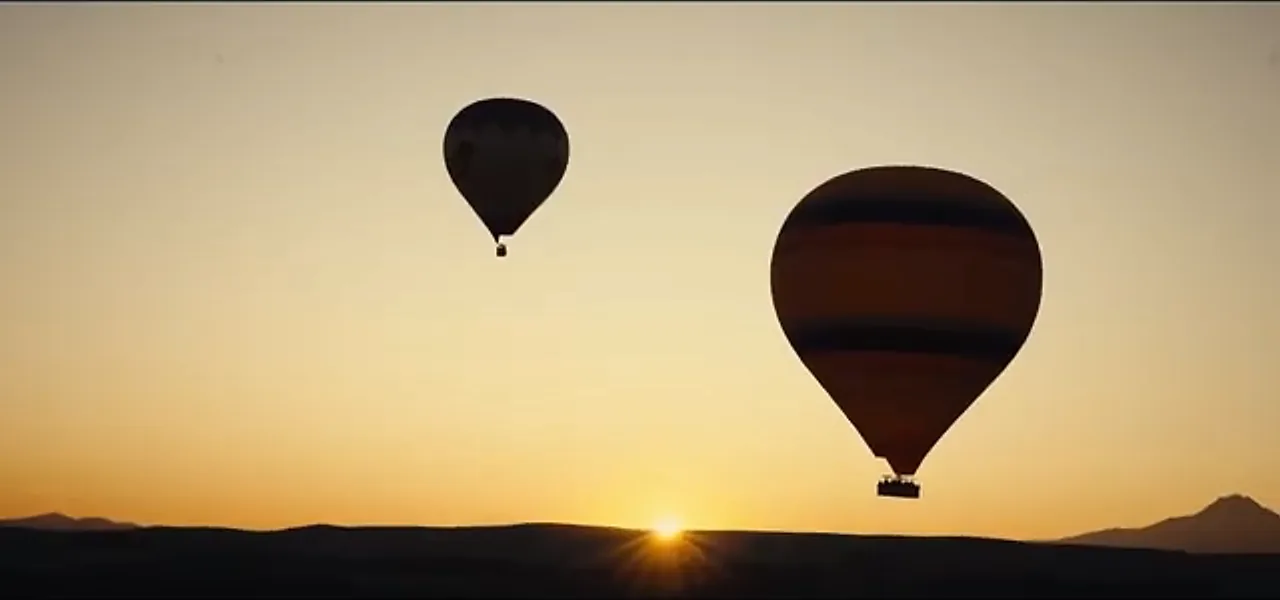 Two hot-air balloons silhouetted against the sunrise over Cappadocia