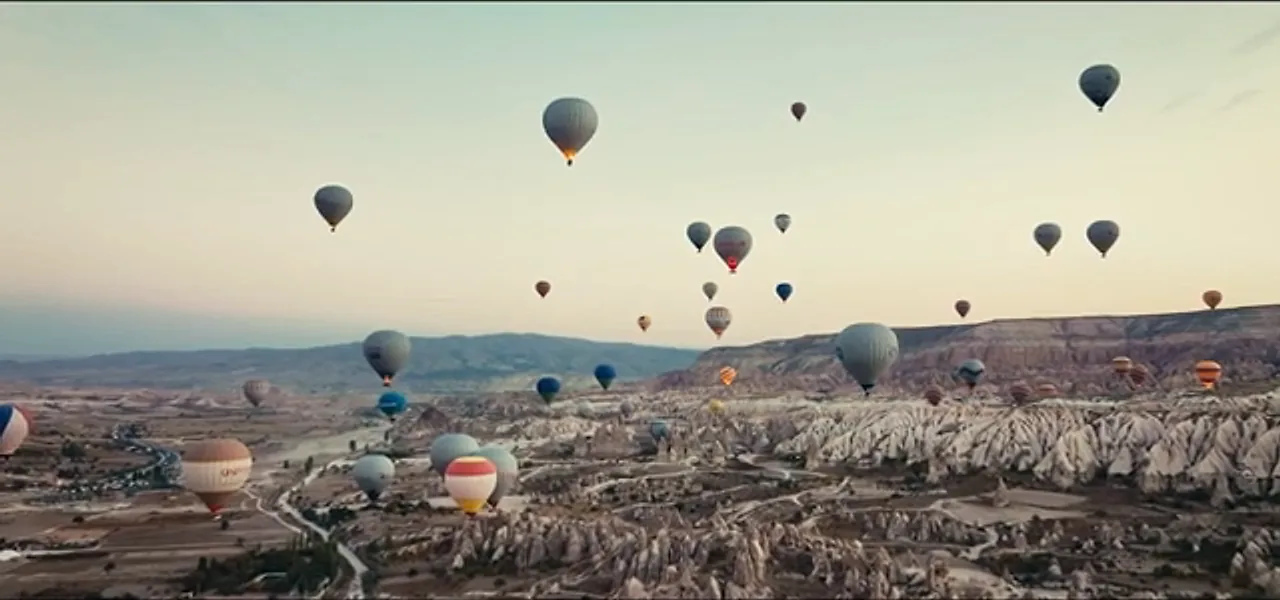 Dozens of hot-air balloons floating over the valleys of Cappadocia at sunrise