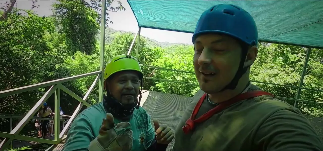 Sorin and a guide in helmets and harnesses on a zip-line canopy platform in the Costa Rican jungle
