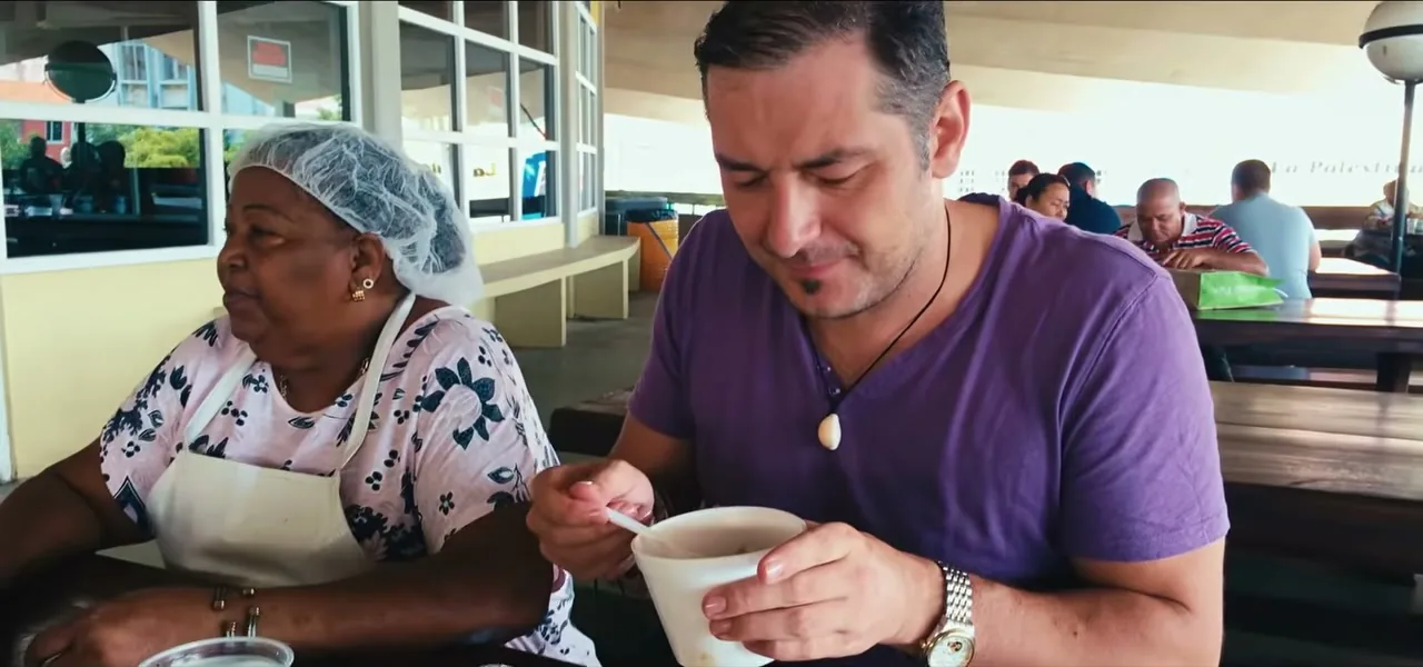 Sorin eating traditional food with the cook Zus di Plaza at the old market in Willemstad, Curaçao