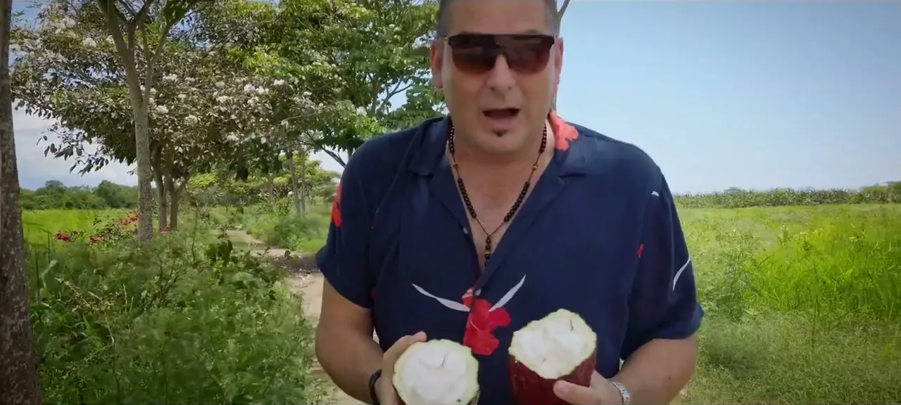 Sorin holding an opened cocoa pod showing the white pulp and seeds, on a plantation in Ecuador