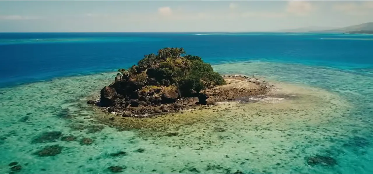 A small rocky islet ringed by turquoise coral reef in Fiji