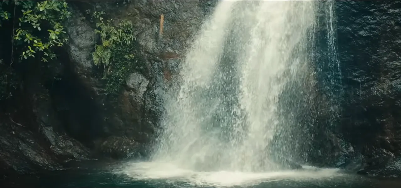 A tall jungle waterfall pouring into a natural pool in Fiji
