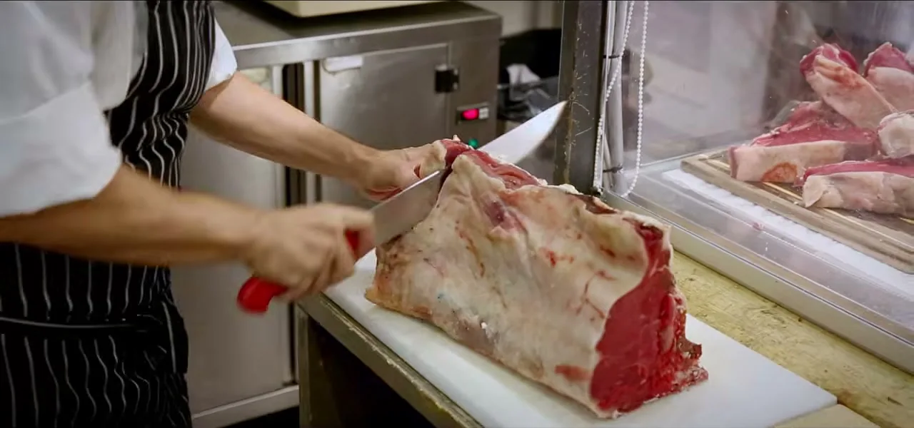 A Michelin-starred chef preparing a Bistecca alla Fiorentina steak in Florence, Italy