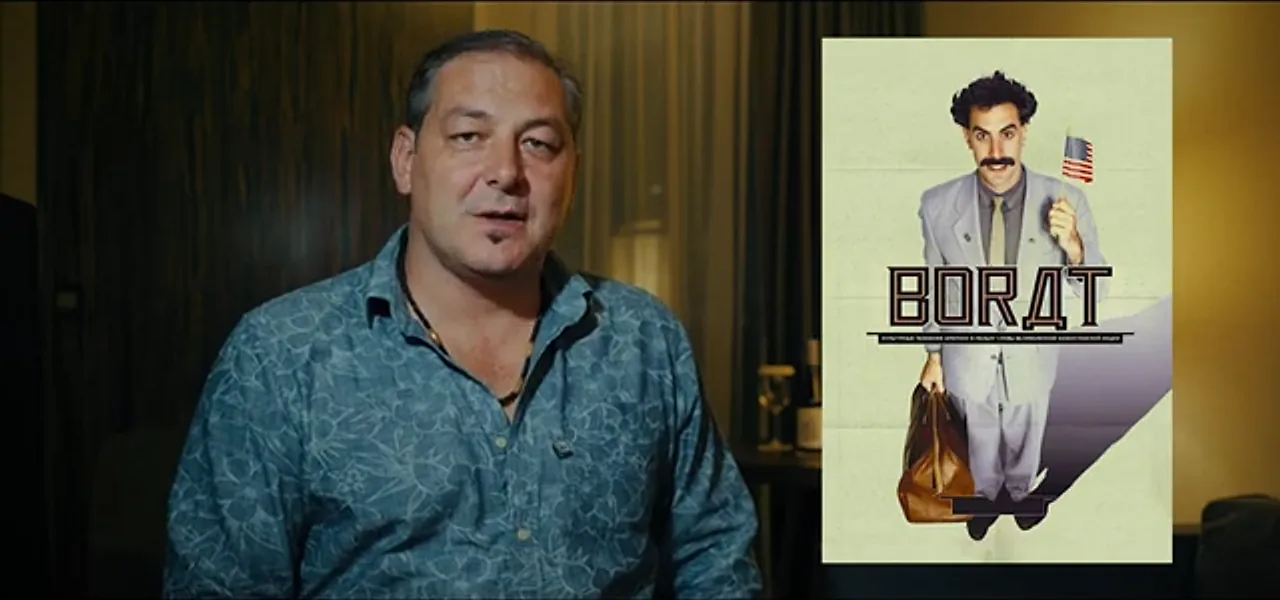 Sorin being interviewed beside a poster of the film Borat