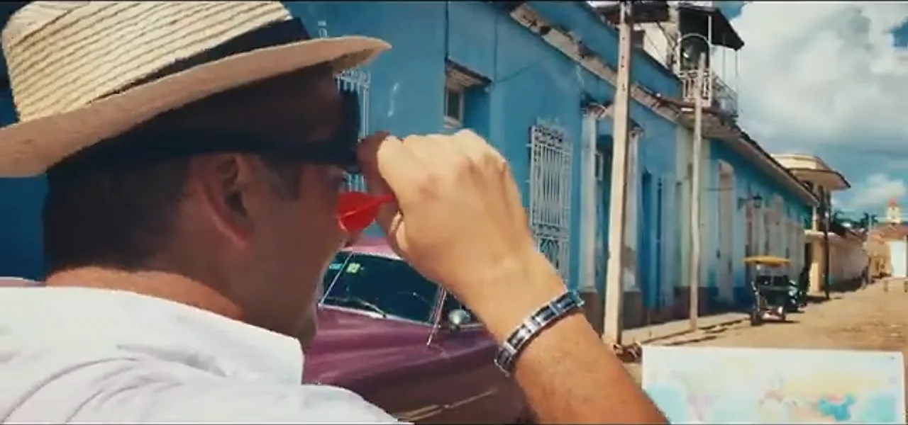 Sorin throwing a dart at a world map between classic cars in Trinidad, Cuba