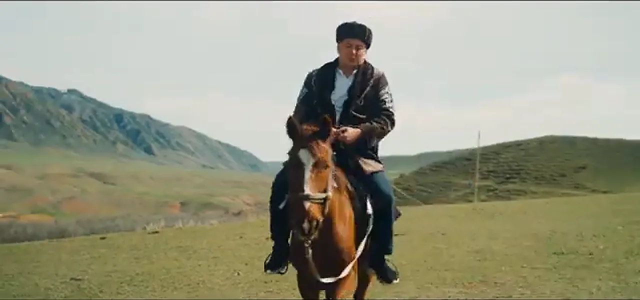 Sorin riding a horse across the Kazakh steppe with mountains behind