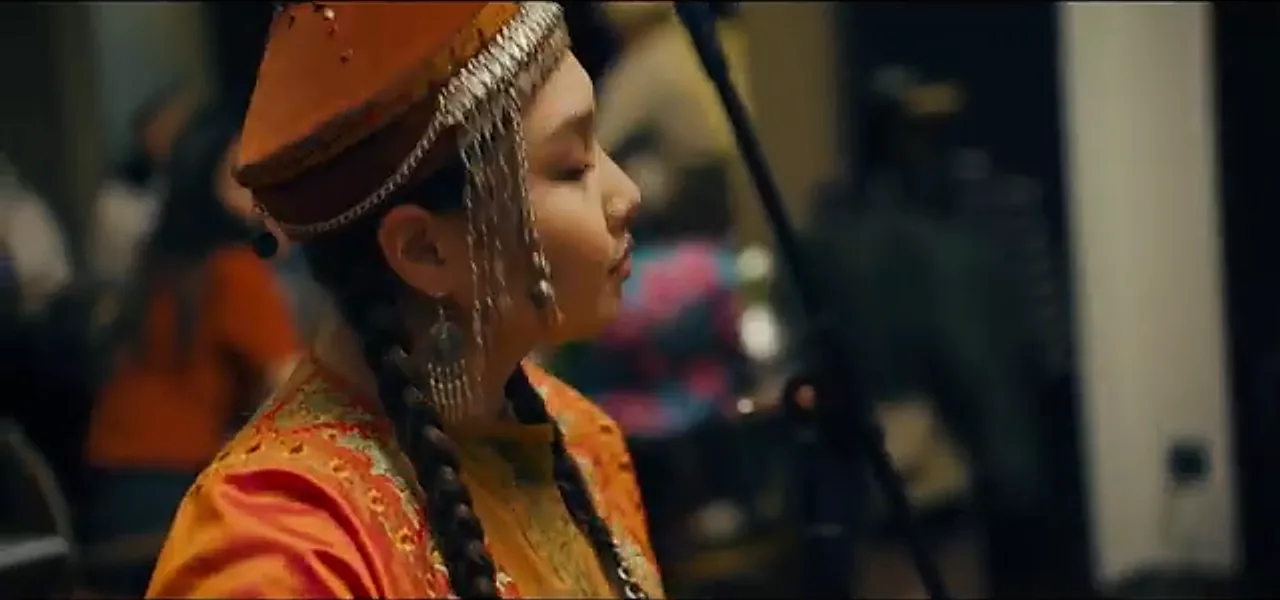 A Kazakh woman in traditional dress playing a stringed instrument at a restaurant in Almaty