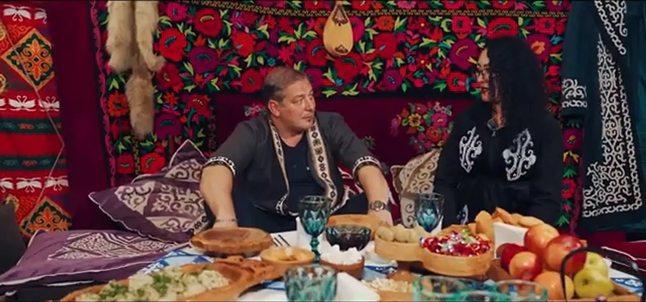 Sorin in traditional Kazakh dress at a feast inside an ornate yurt