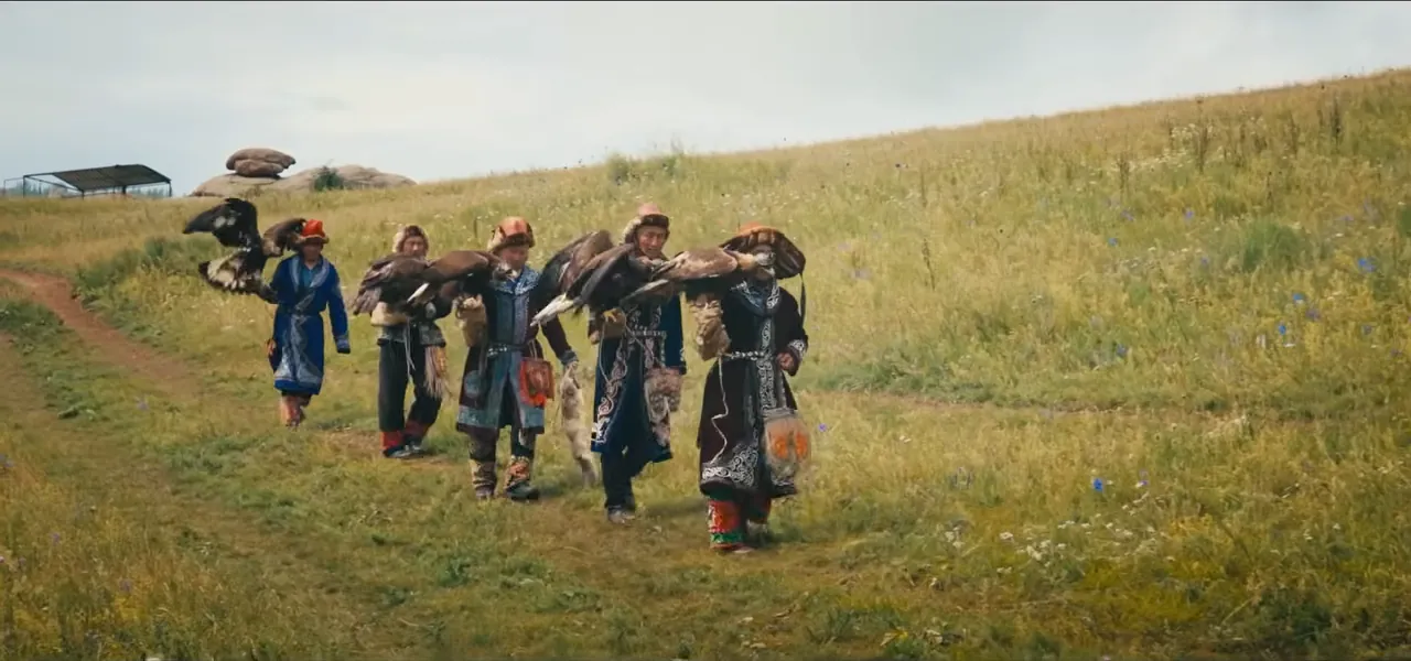 A line of Kazakh eagle hunters in traditional dress walking across the Mongolian grassland