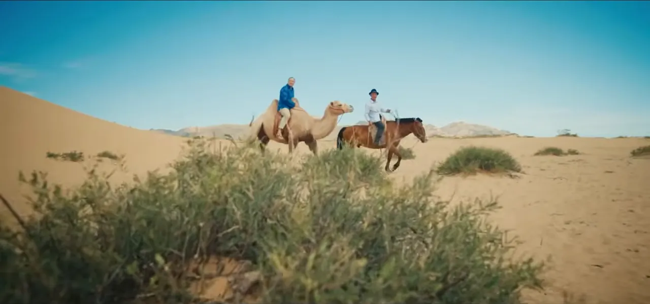 A rider leading camels across a sand dune in the Gobi Desert, Mongolia