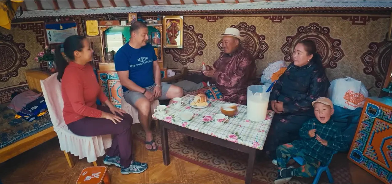 Sorin sitting with a Mongolian nomadic family inside their ger, sharing food and drink