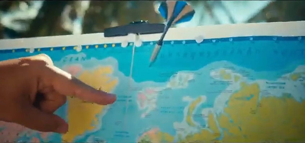 A hand pointing at the top of a world map near Svalbard after a dart throw