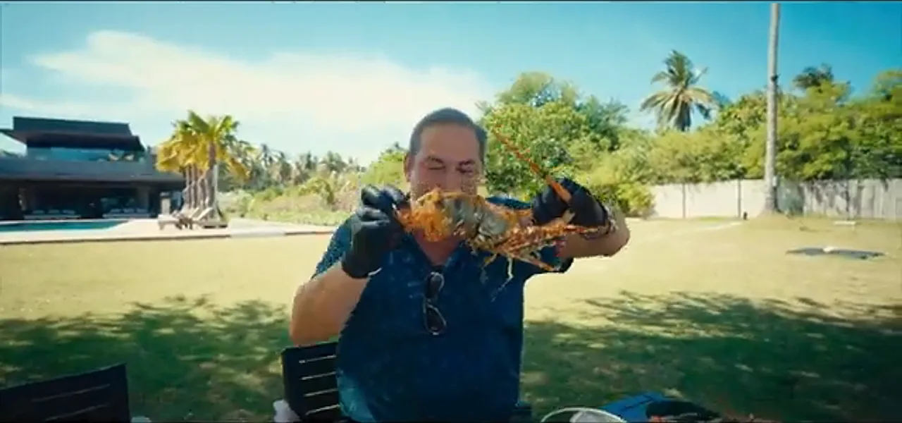 Sorin holding up a cooked lobster at a seafood feast in Palawan, Philippines