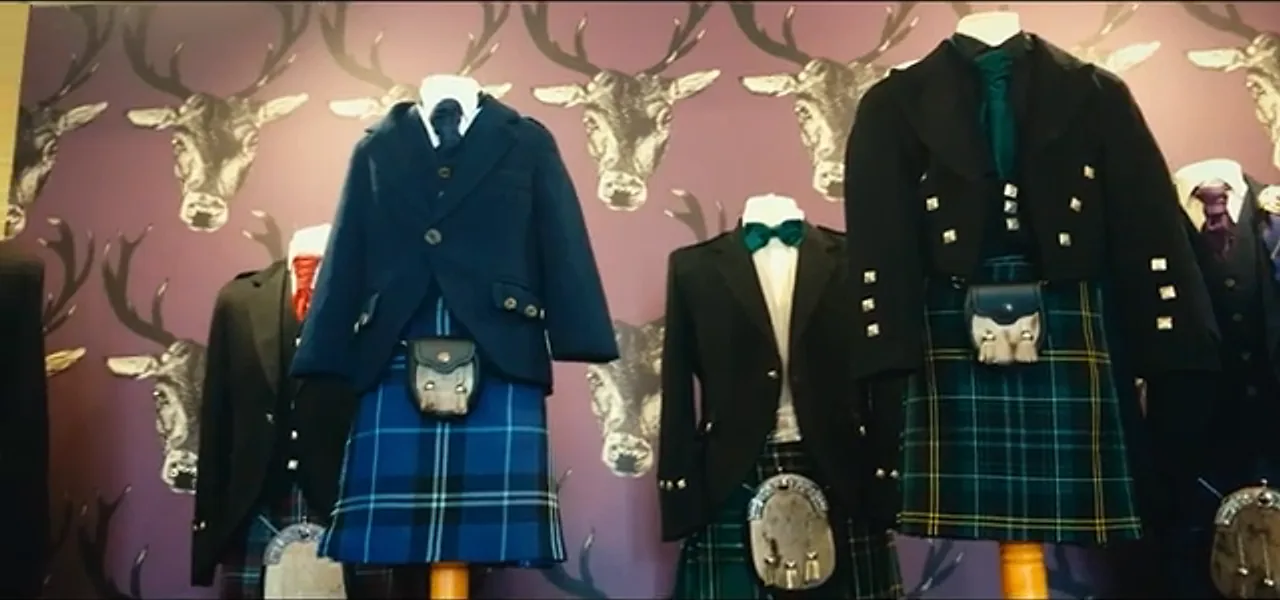 Formal Highland kilt outfits displayed on mannequins beneath mounted stag heads