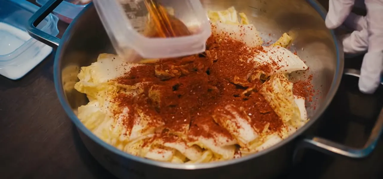 Napa cabbage being coated in red pepper powder to make kimchi